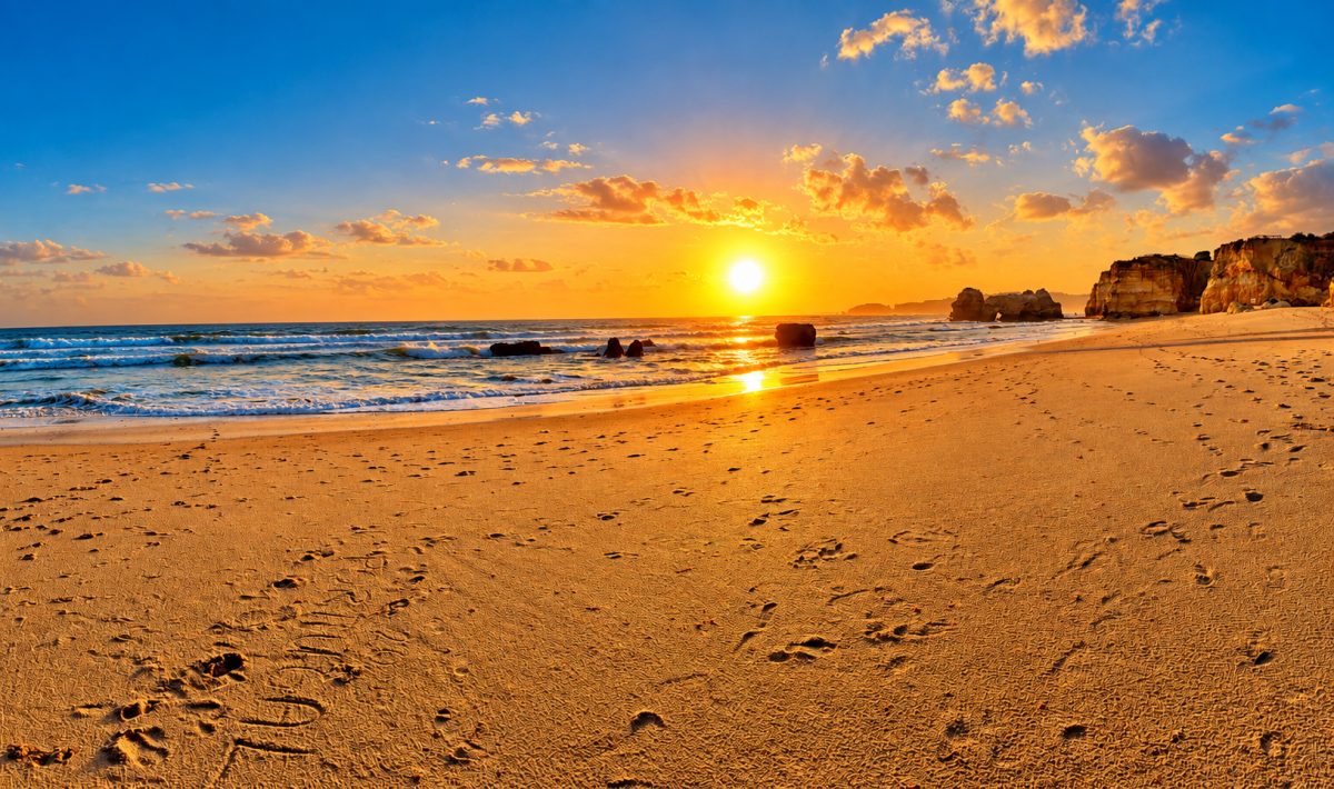 Tief stehende Sonne über Strand und Felsen